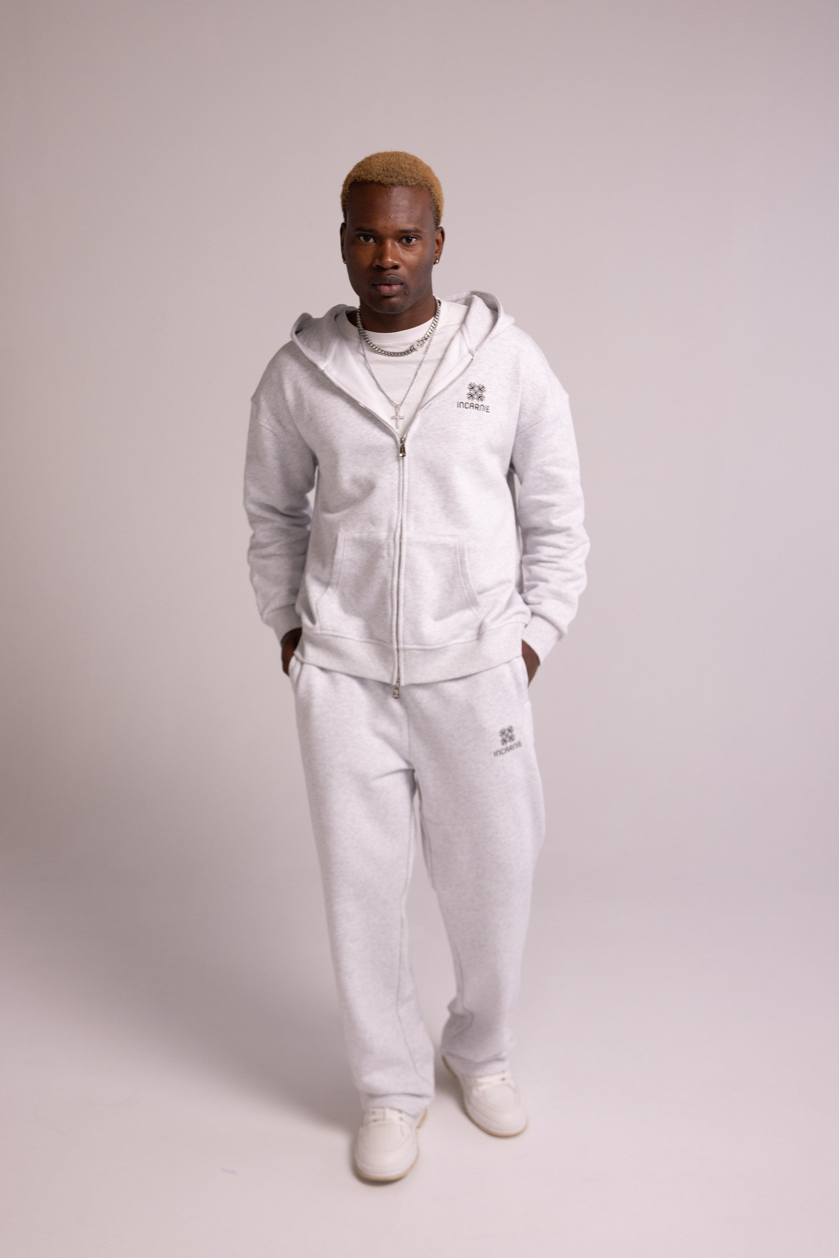 Person wearing a grey tracksuit on a plain background