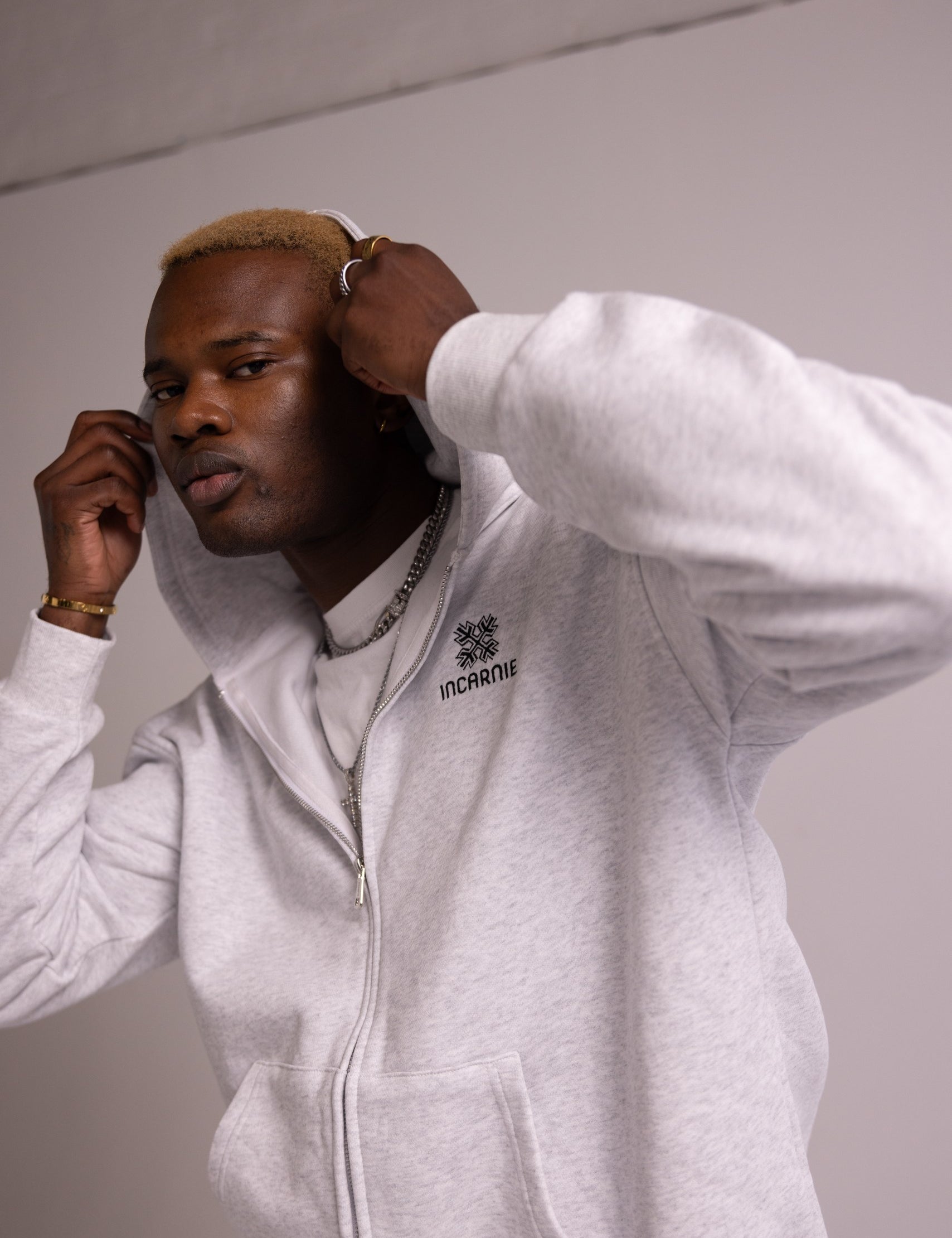 Person wearing a grey hoodie with a logo on a plain background