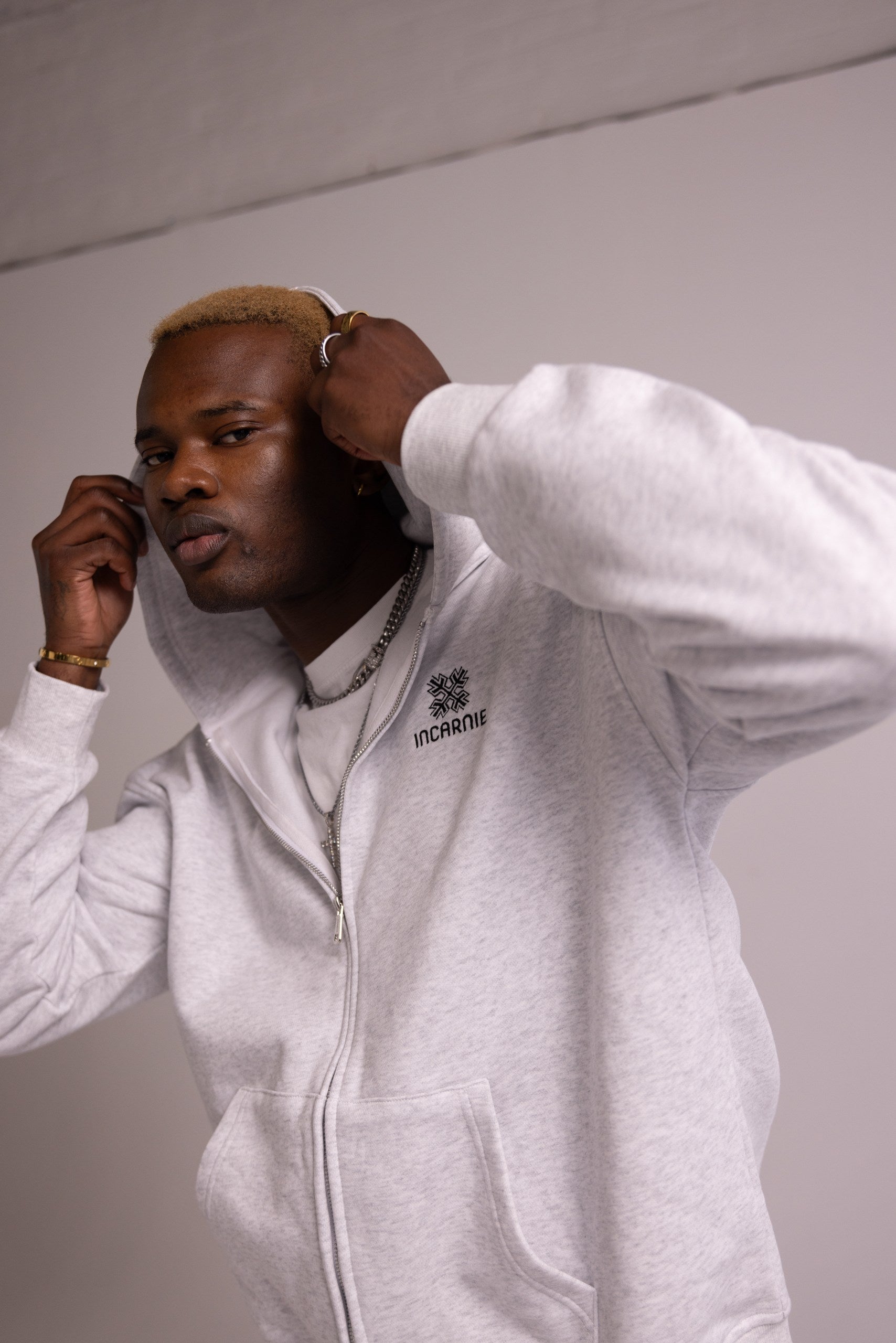 Person wearing a grey hoodie with a logo on a plain background