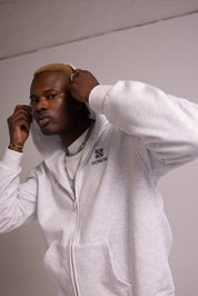 Person wearing a grey hoodie with a logo on a plain background