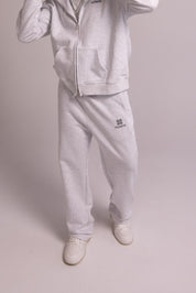 Person wearing a grey tracksuit with a brand logo on a plain background