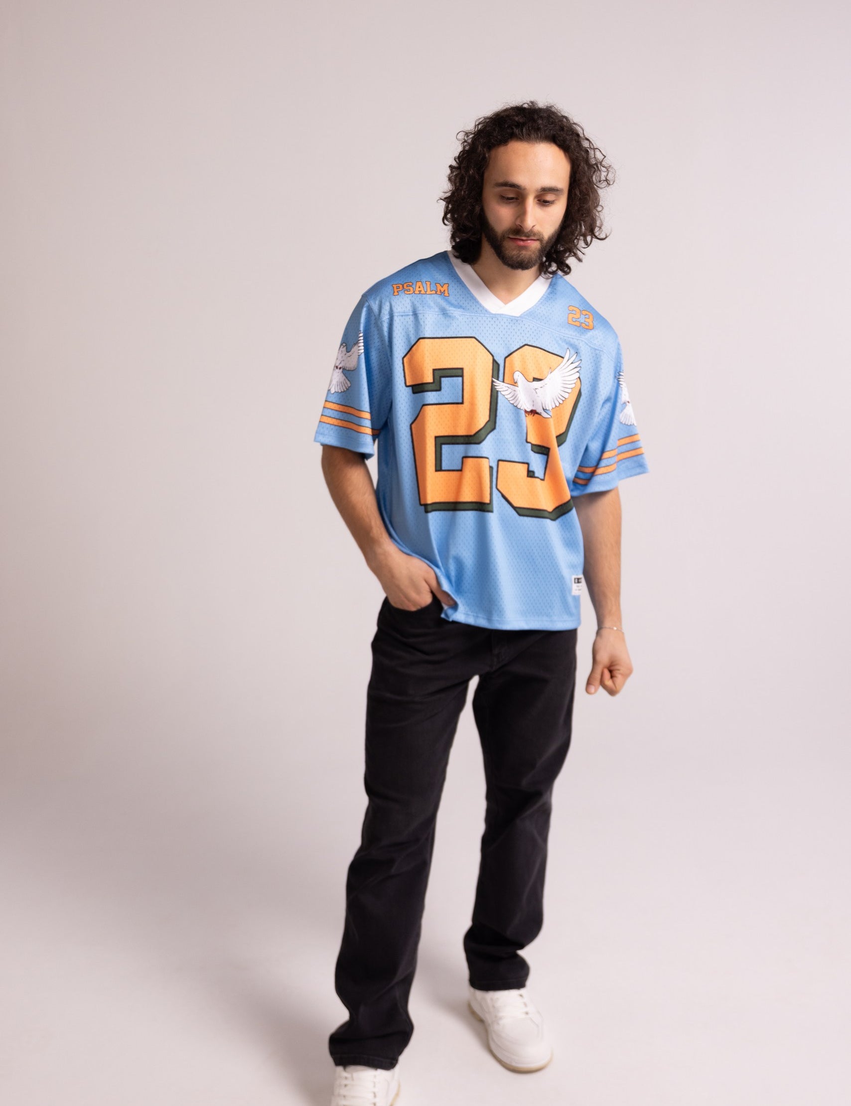 Man wearing a light blue sports jersey with orange number 23 on a plain background