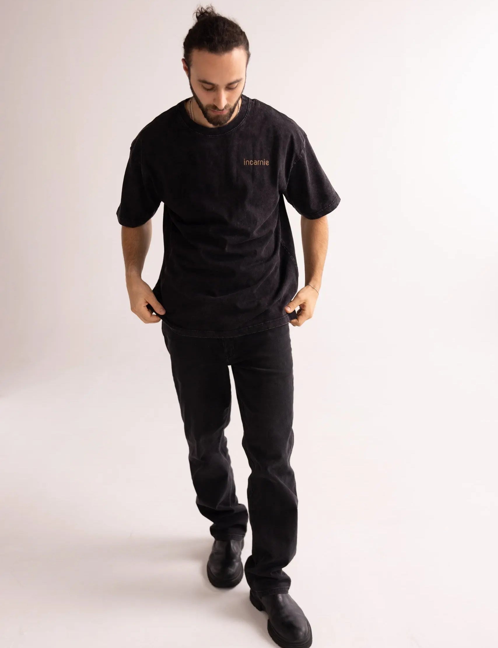 Man wearing a black t-shirt and pants on a white background
