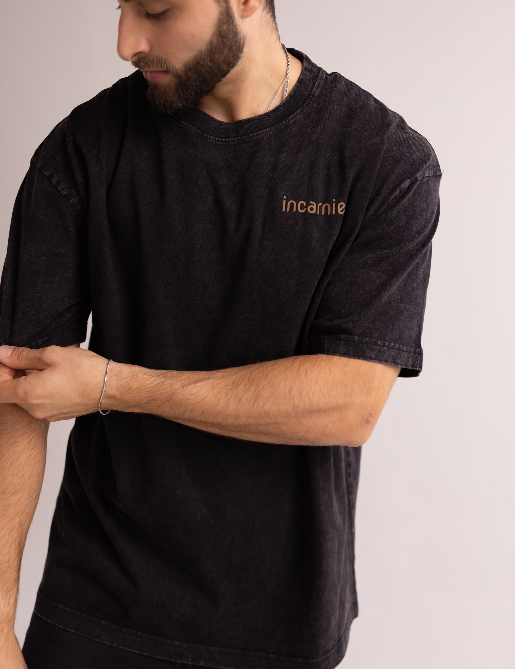 Man wearing a black t-shirt with 'incarnie' logo on a plain background