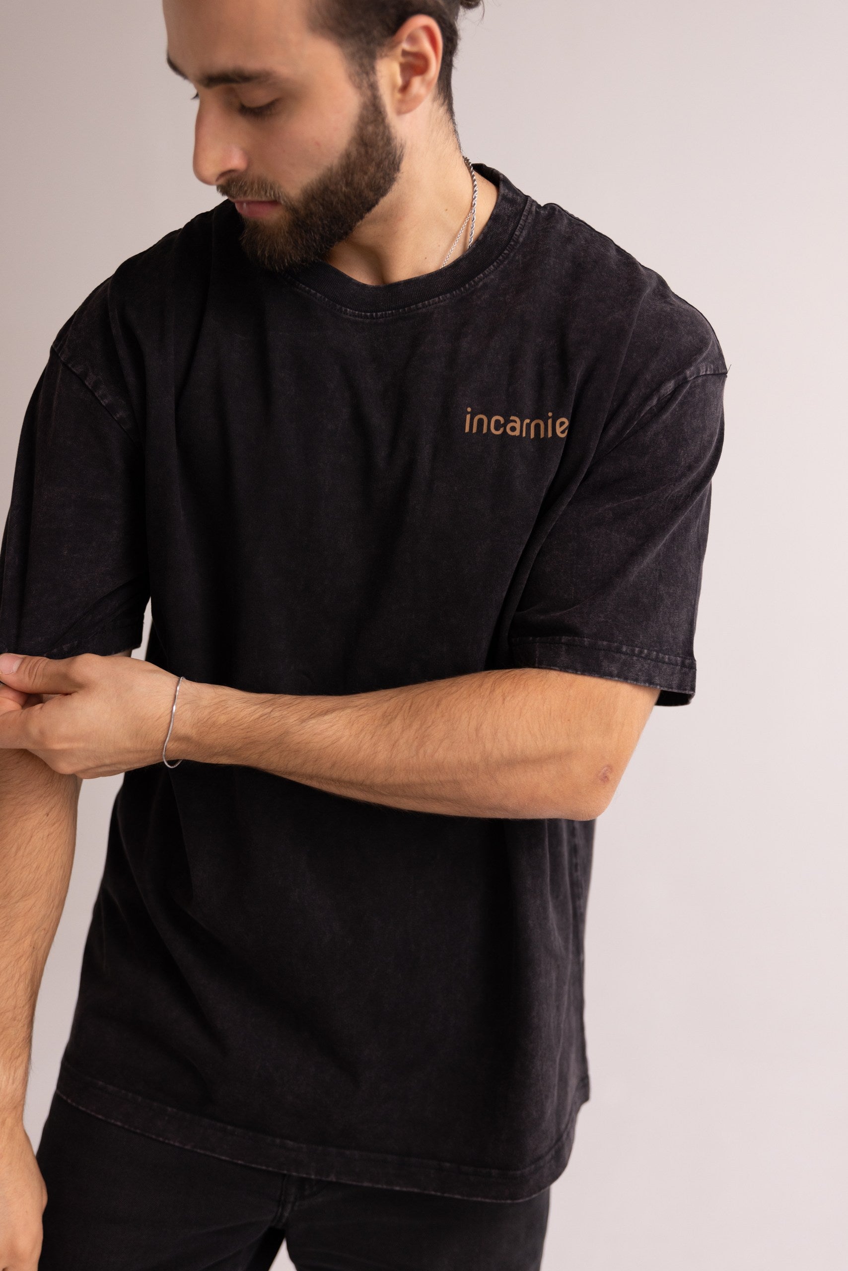 Man wearing a black t-shirt with 'incarnie' logo on a plain background