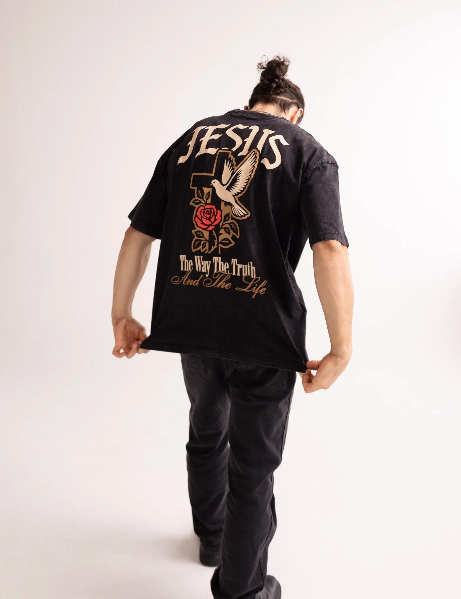 Person wearing a black t-shirt with a graphic design on the back, standing against a white background
