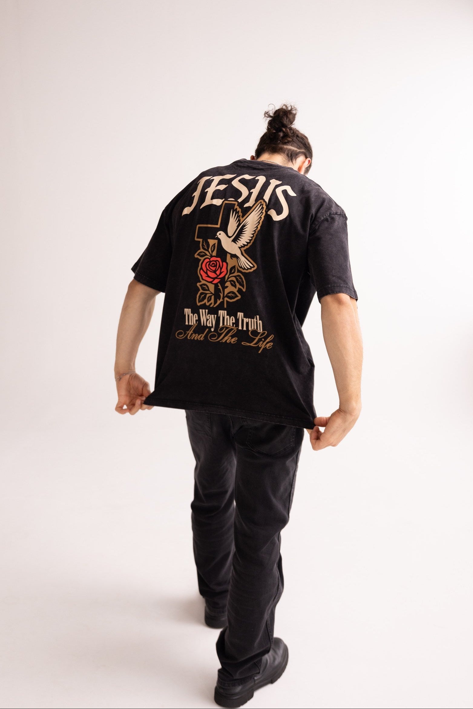 Person wearing a black t-shirt with a graphic design on the back, standing against a white background