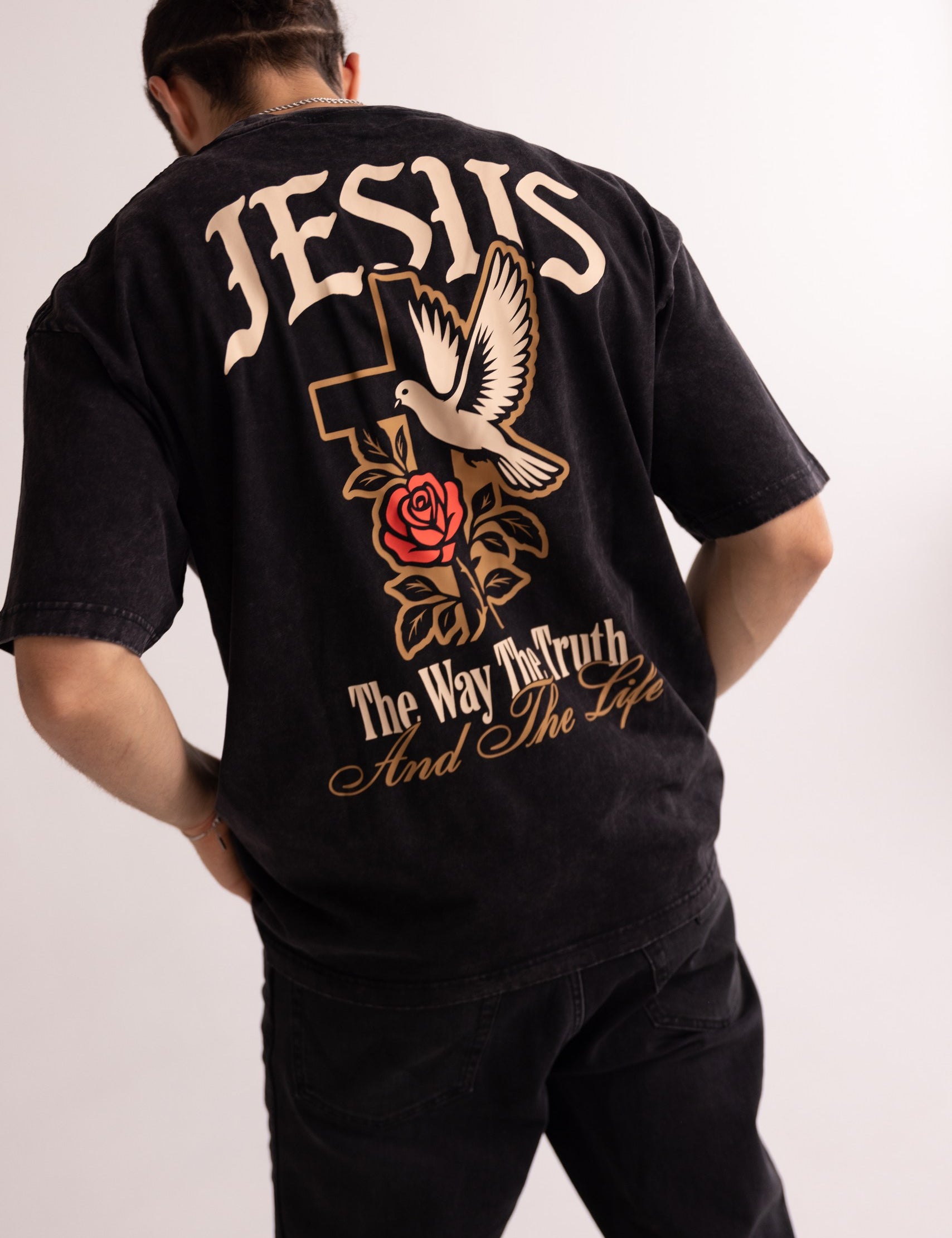 Person wearing a black t-shirt with religious text and symbols on the back.