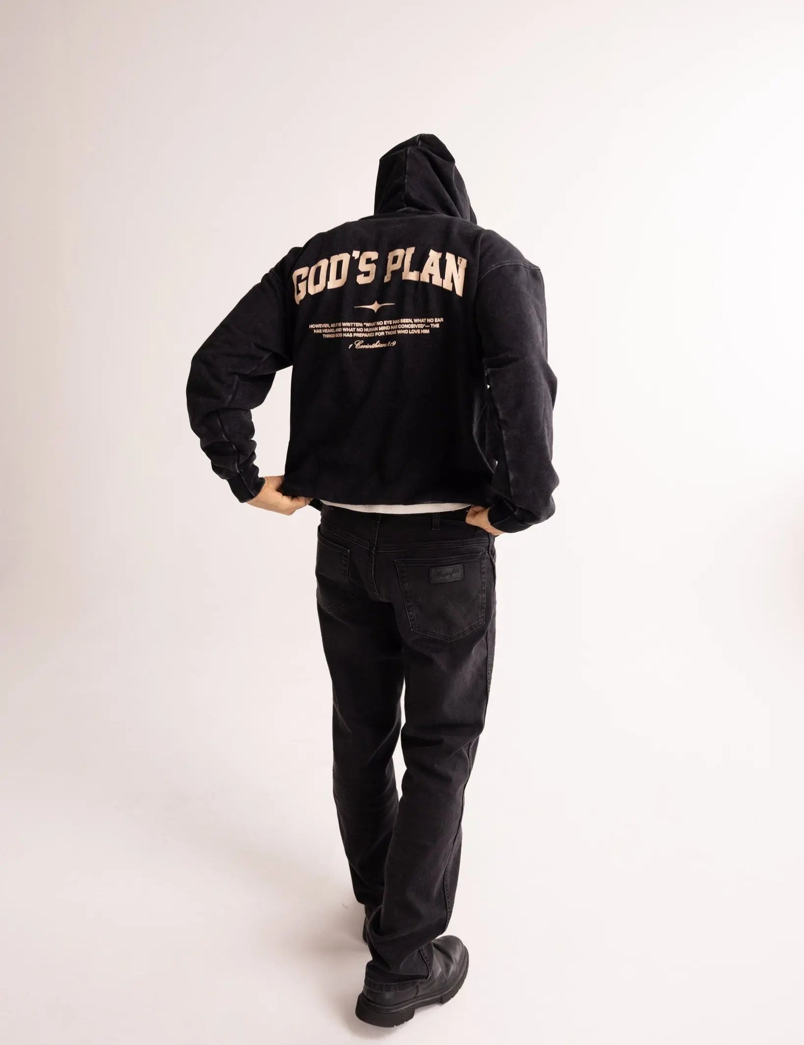 Person wearing a black hoodie with 'GOD'S PLAN' text on the back against a white background