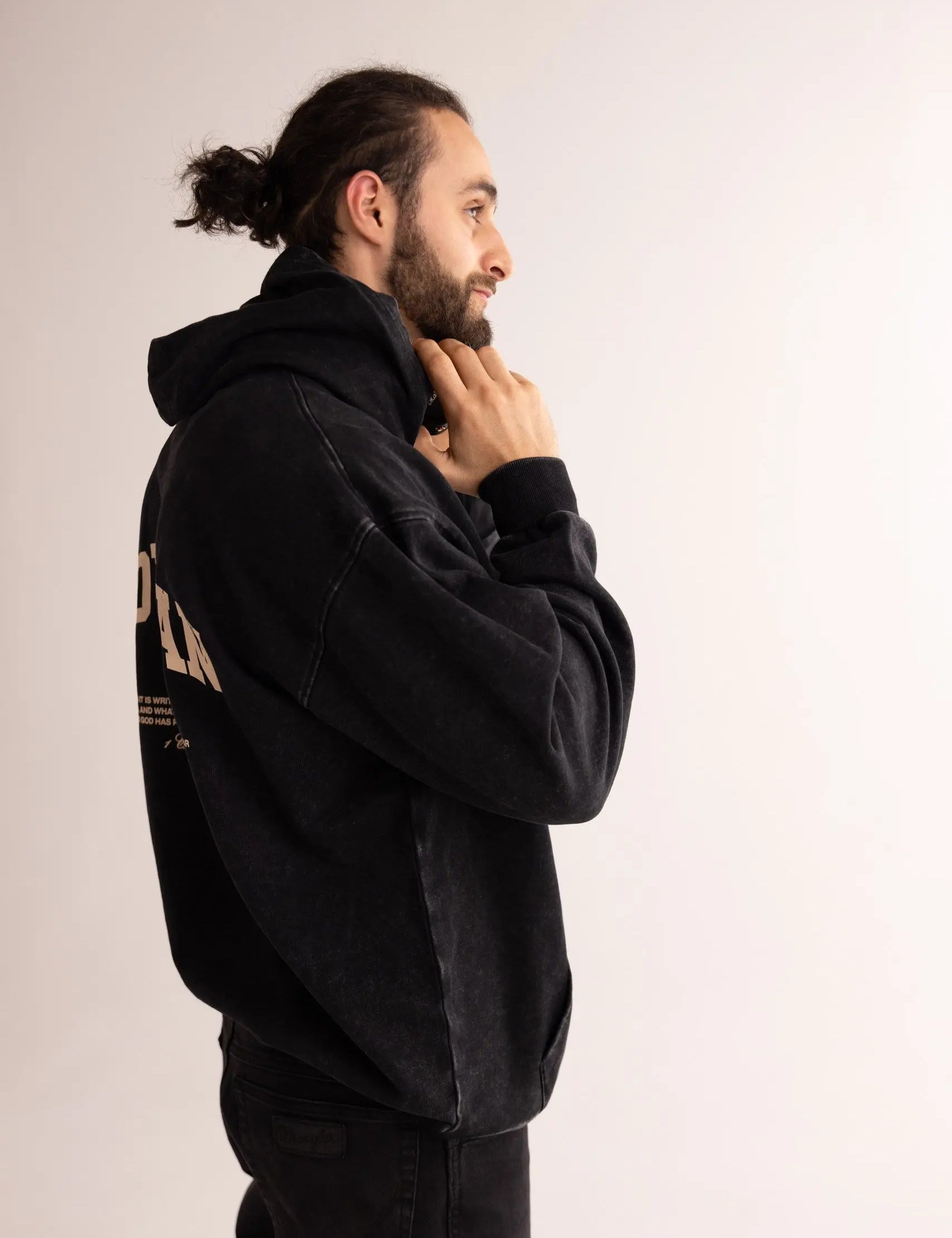 Man wearing a black hoodie with text on the back against a plain background