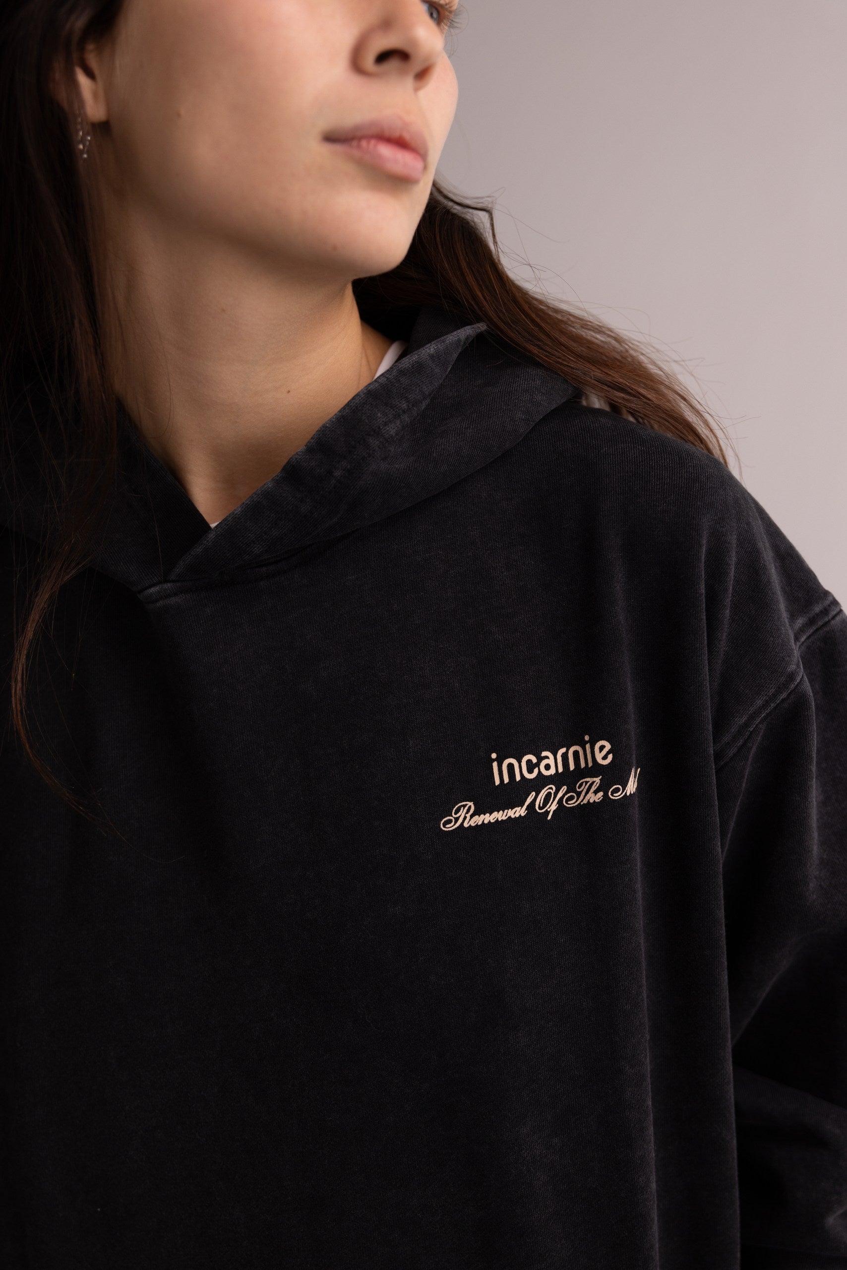 Person wearing a black hoodie with 'incarnie' logo on a neutral background