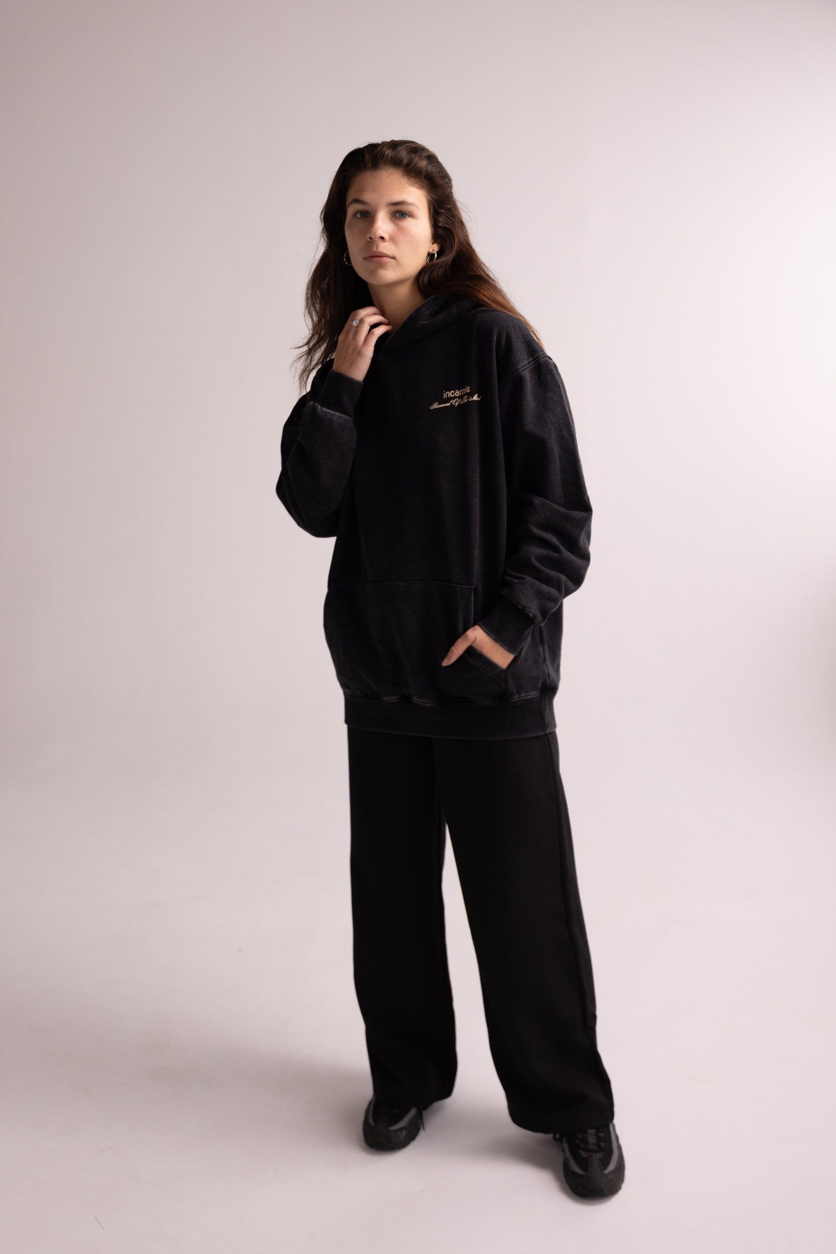 Person wearing a black hoodie and pants on a plain background