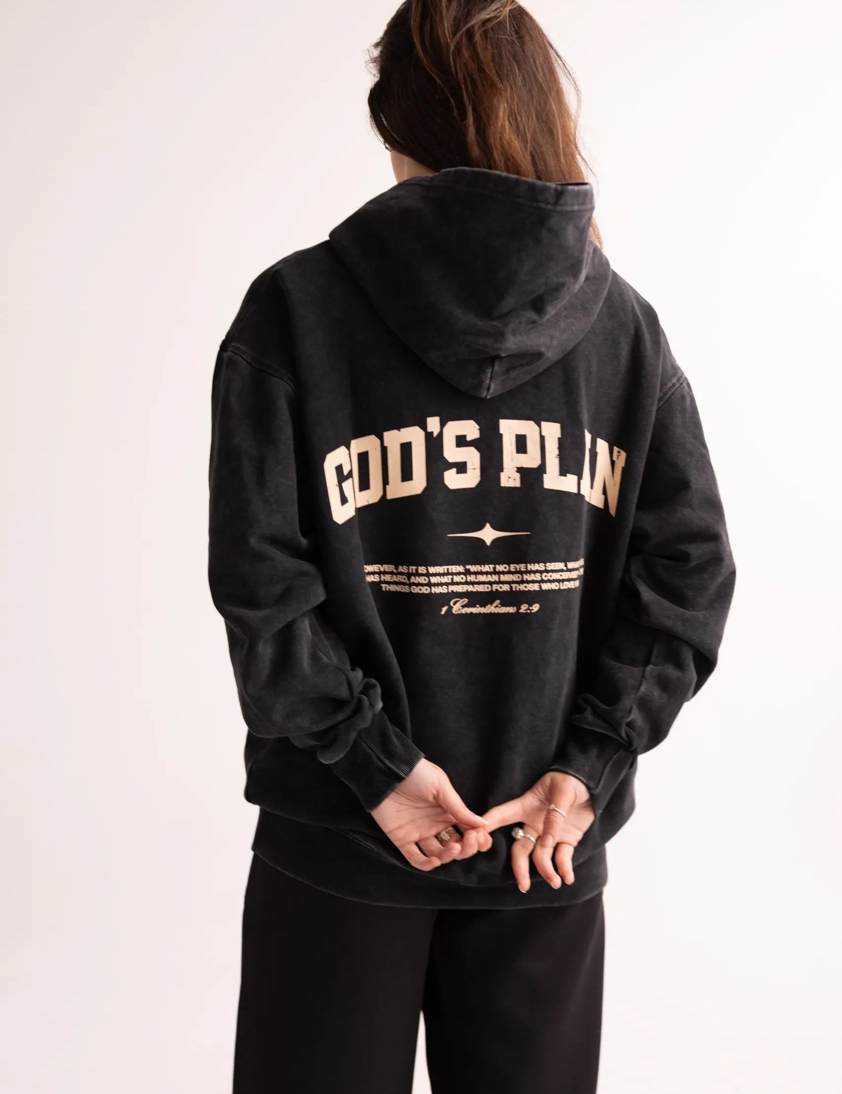 Person wearing a black hoodie with 'GOD'S PLAN' text on the back against a white background