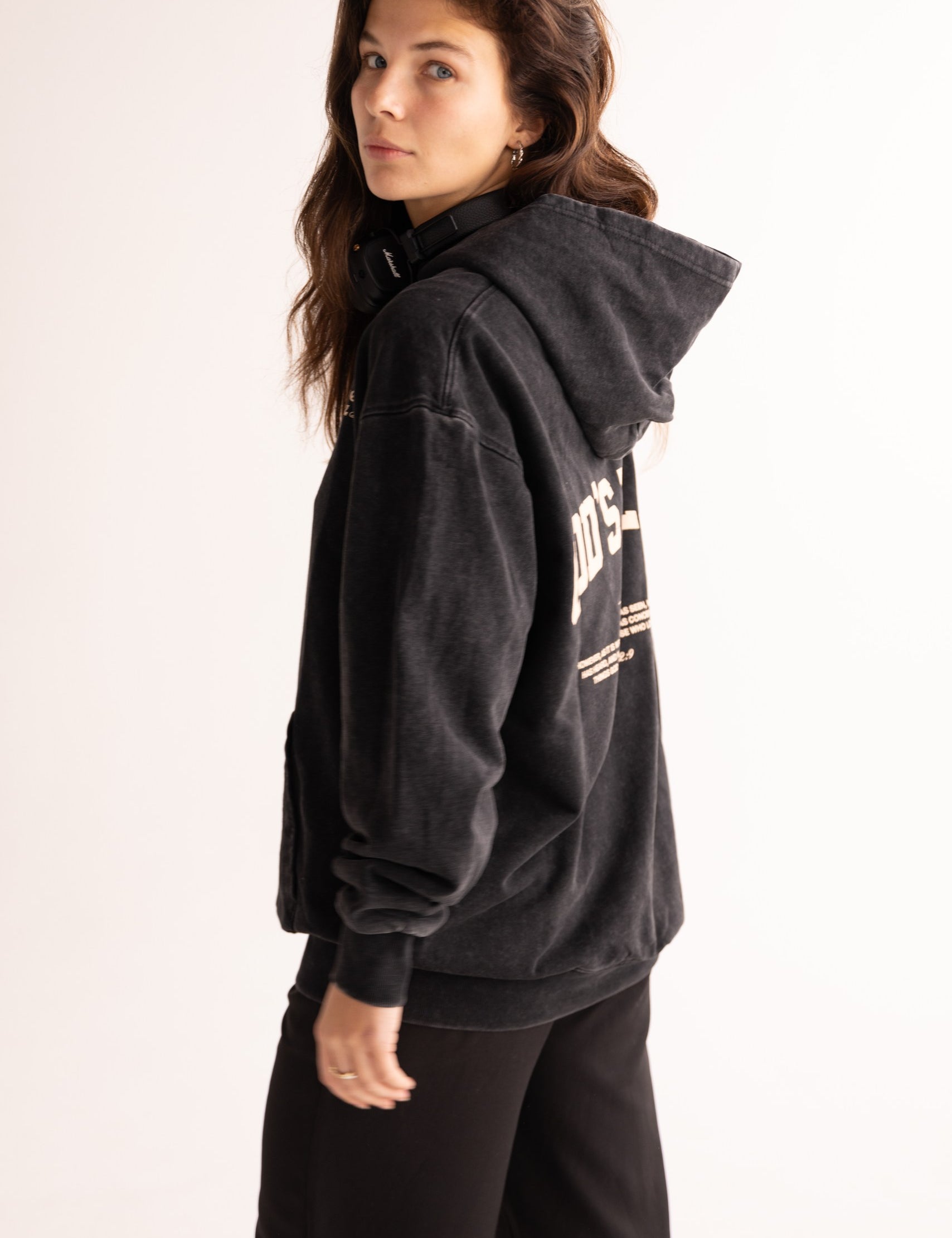 Person wearing a black hoodie with text on the back against a plain background