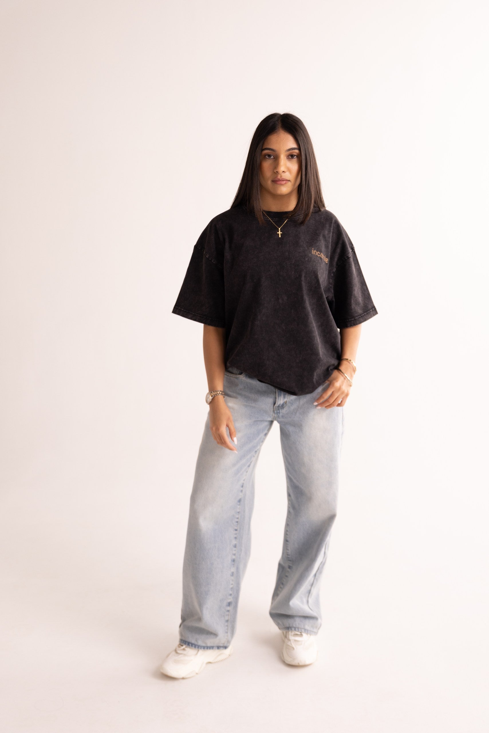 Person wearing a black t-shirt and light blue jeans on a white background