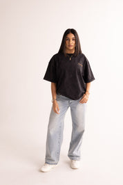 Person wearing a black t-shirt and light blue jeans on a white background