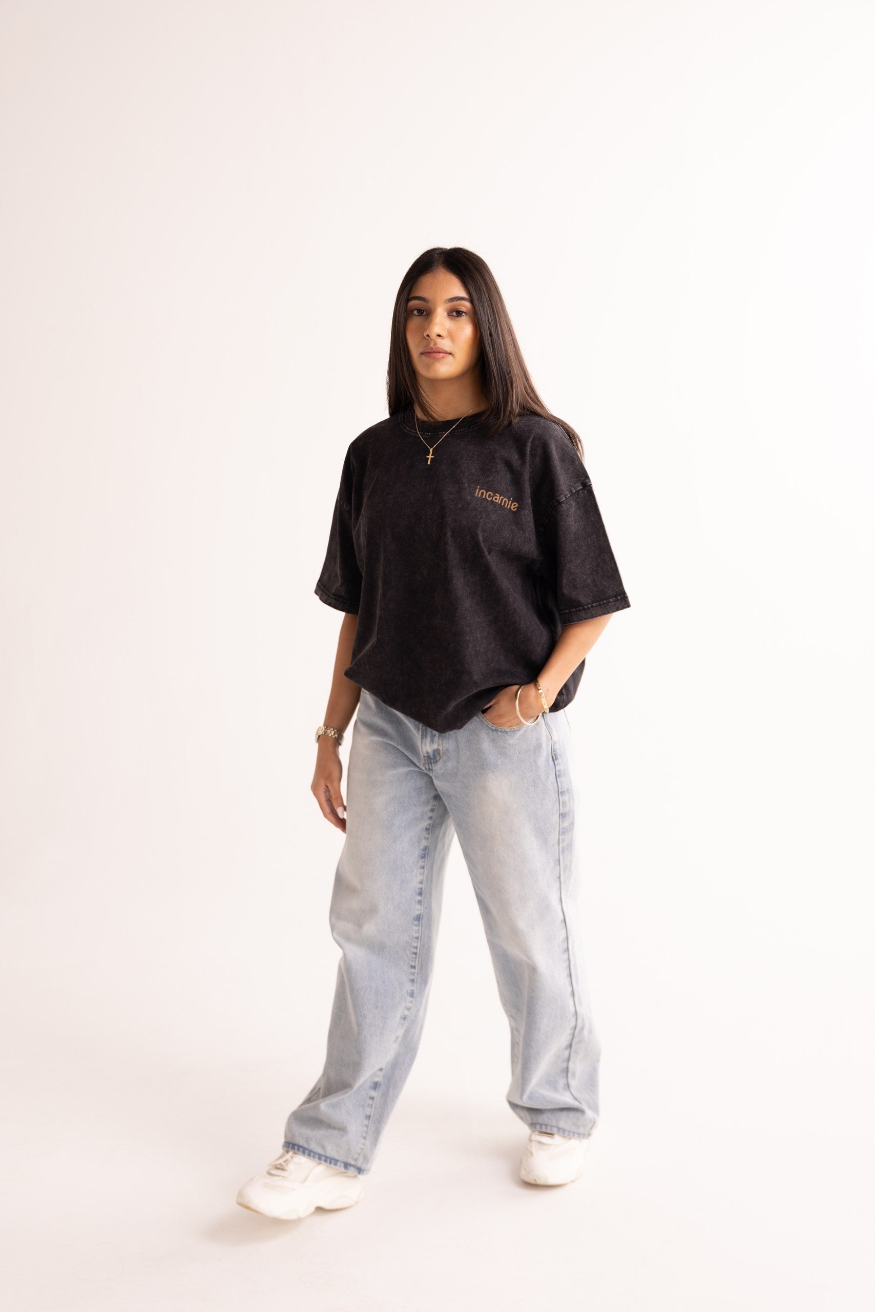 Person wearing a black oversized shirt and light blue jeans on a white background