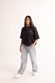 Person wearing a black oversized shirt and light blue jeans on a white background