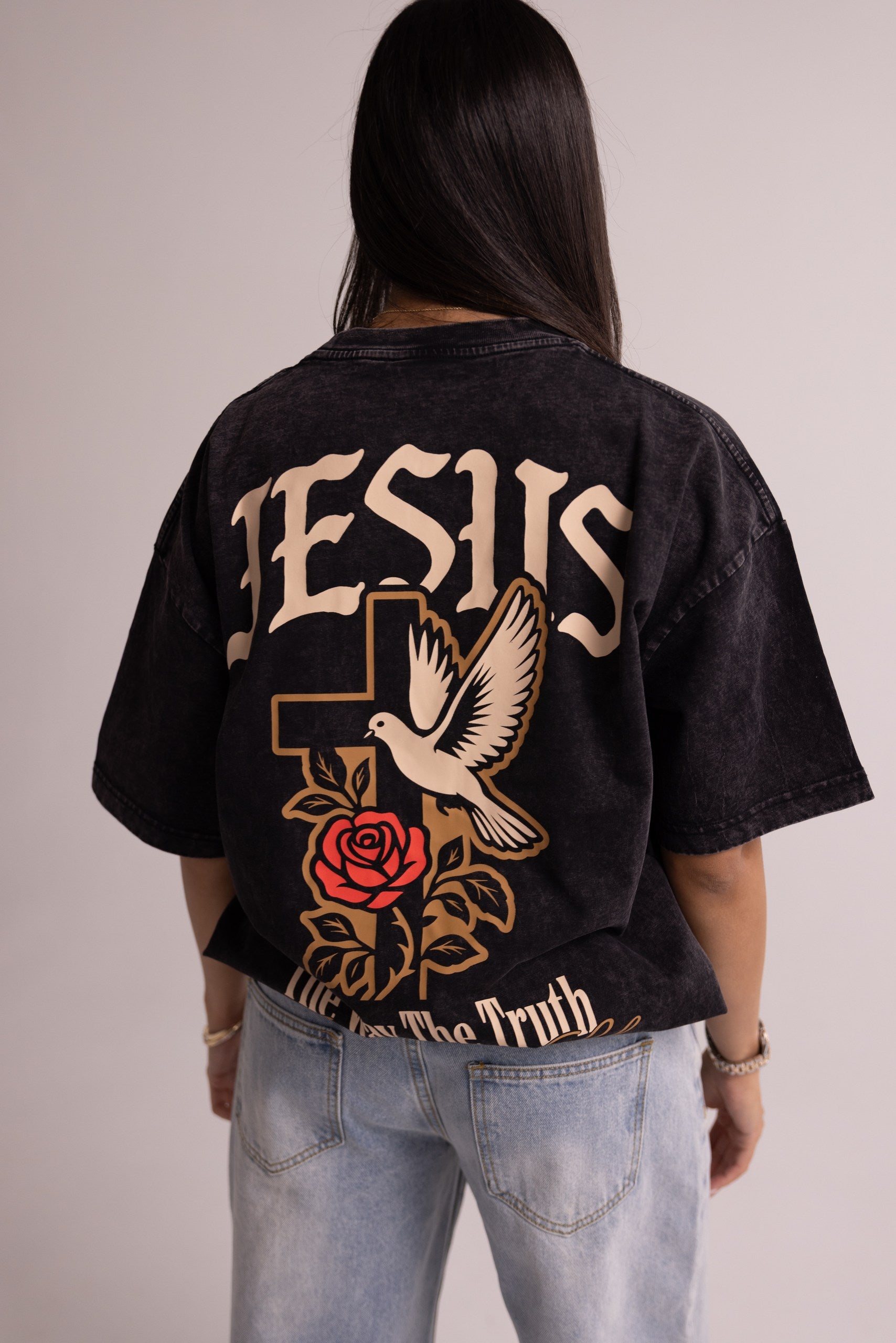 Person wearing a black t-shirt with 'Jesus' and religious symbols on the back.