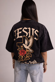Person wearing a black t-shirt with 'Jesus' and religious symbols on the back.