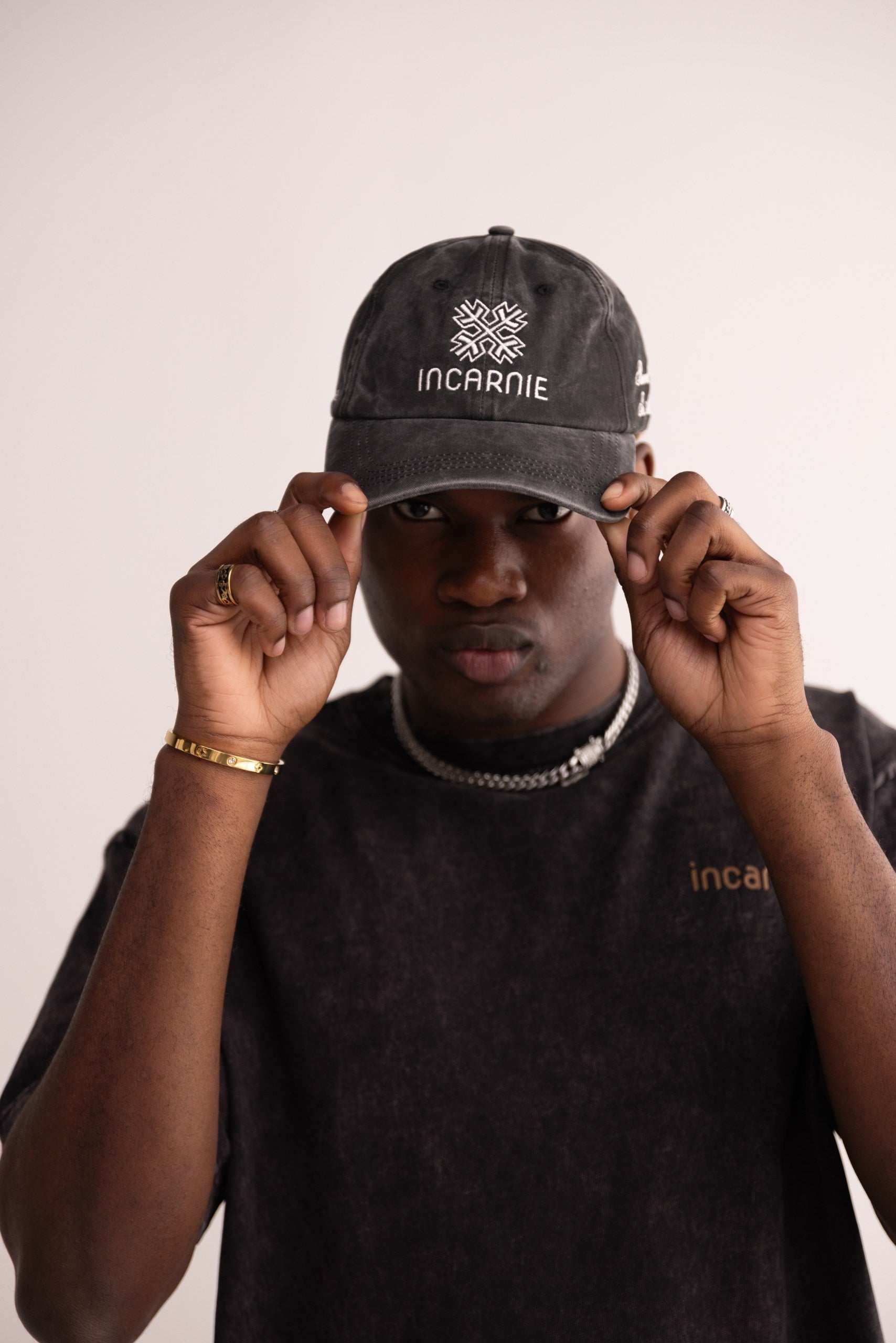 Person wearing a black cap with 'INCARNIE' branding on a plain background