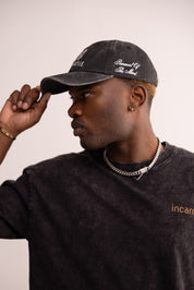 Man wearing a black cap and black shirt with 'incarnie' branding.