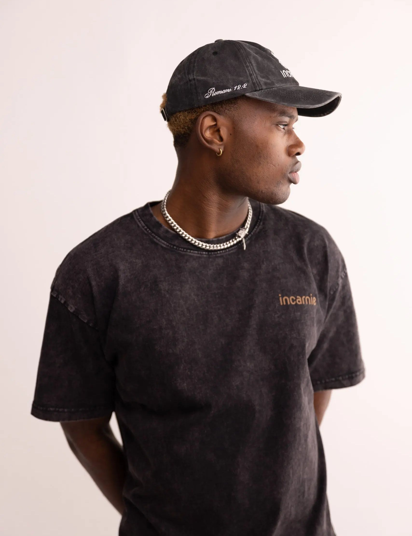 Person wearing a black cap and t-shirt with 'incarnate' branding on a plain background