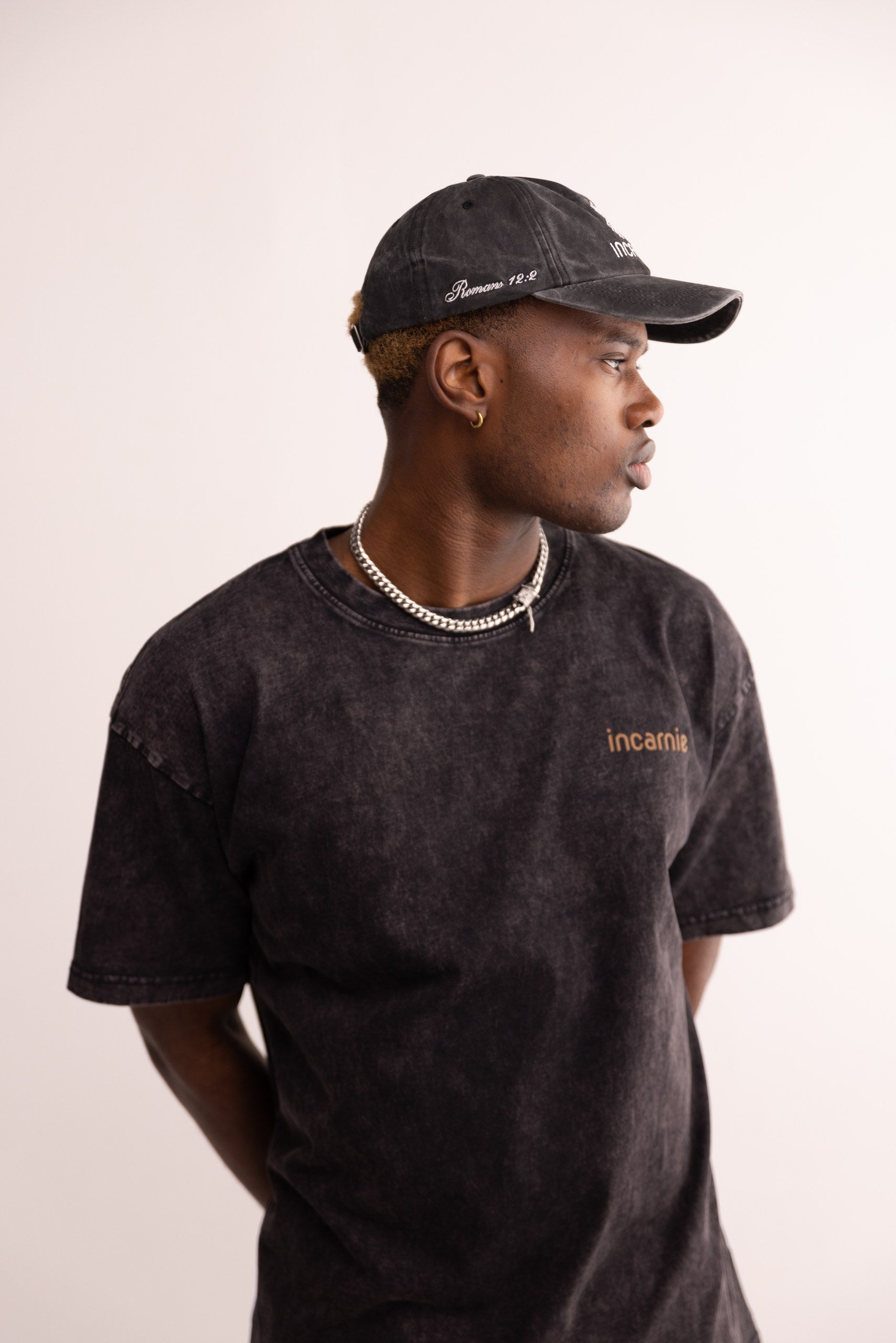 Person wearing a black cap and t-shirt with 'incarnate' branding on a plain background
