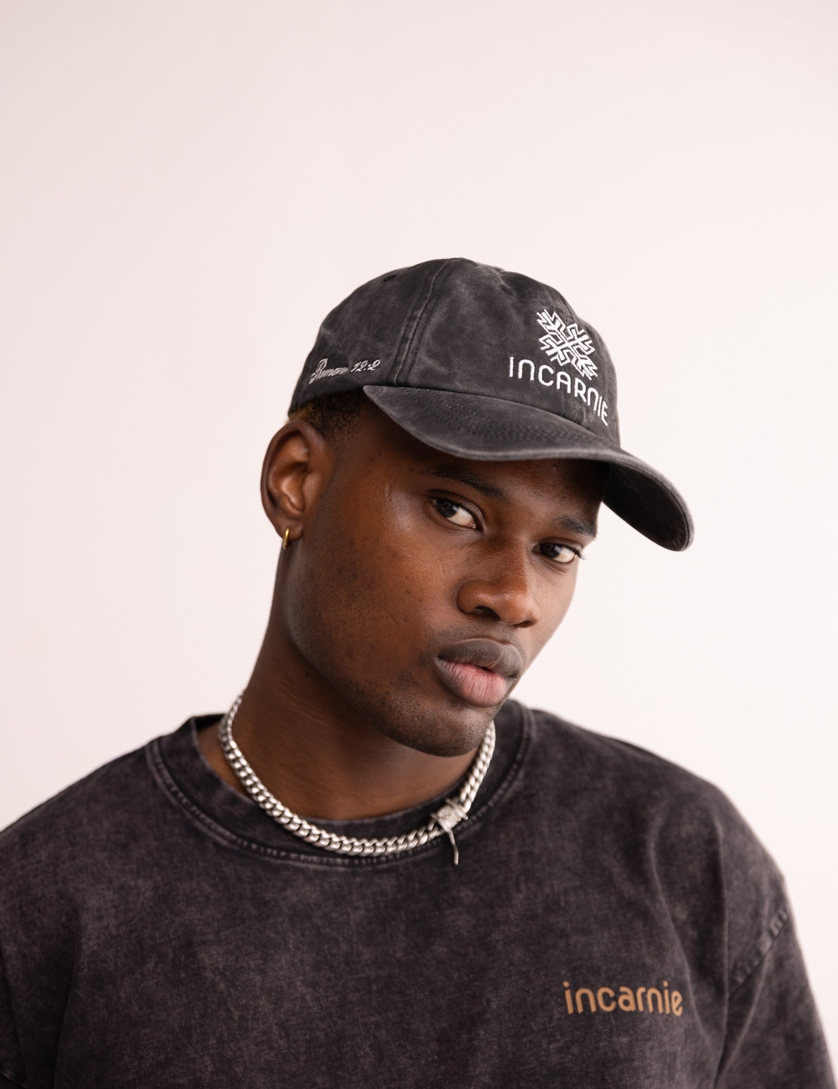 Man wearing a black cap and sweatshirt with 'incarnie' branding on a light background