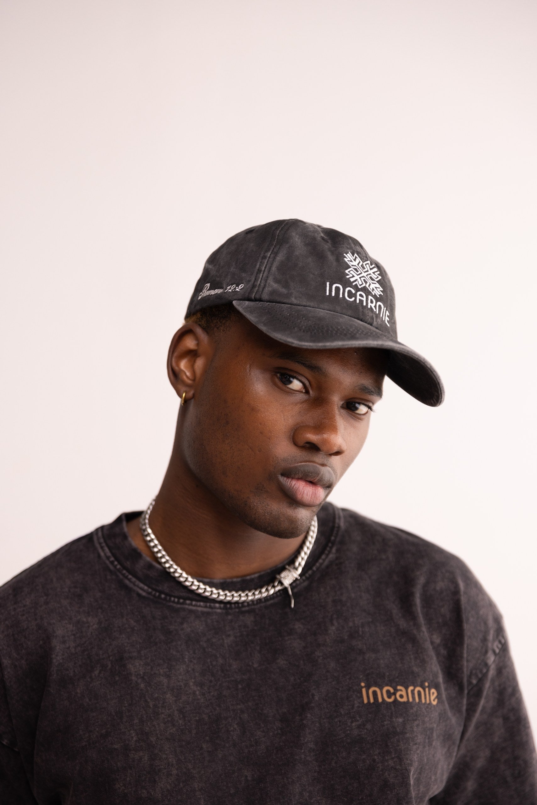 Man wearing a black cap and sweatshirt with 'incarnie' branding on a light background