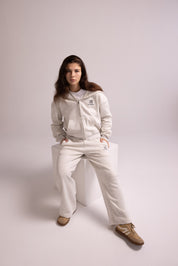 Person wearing a light gray tracksuit on a white background