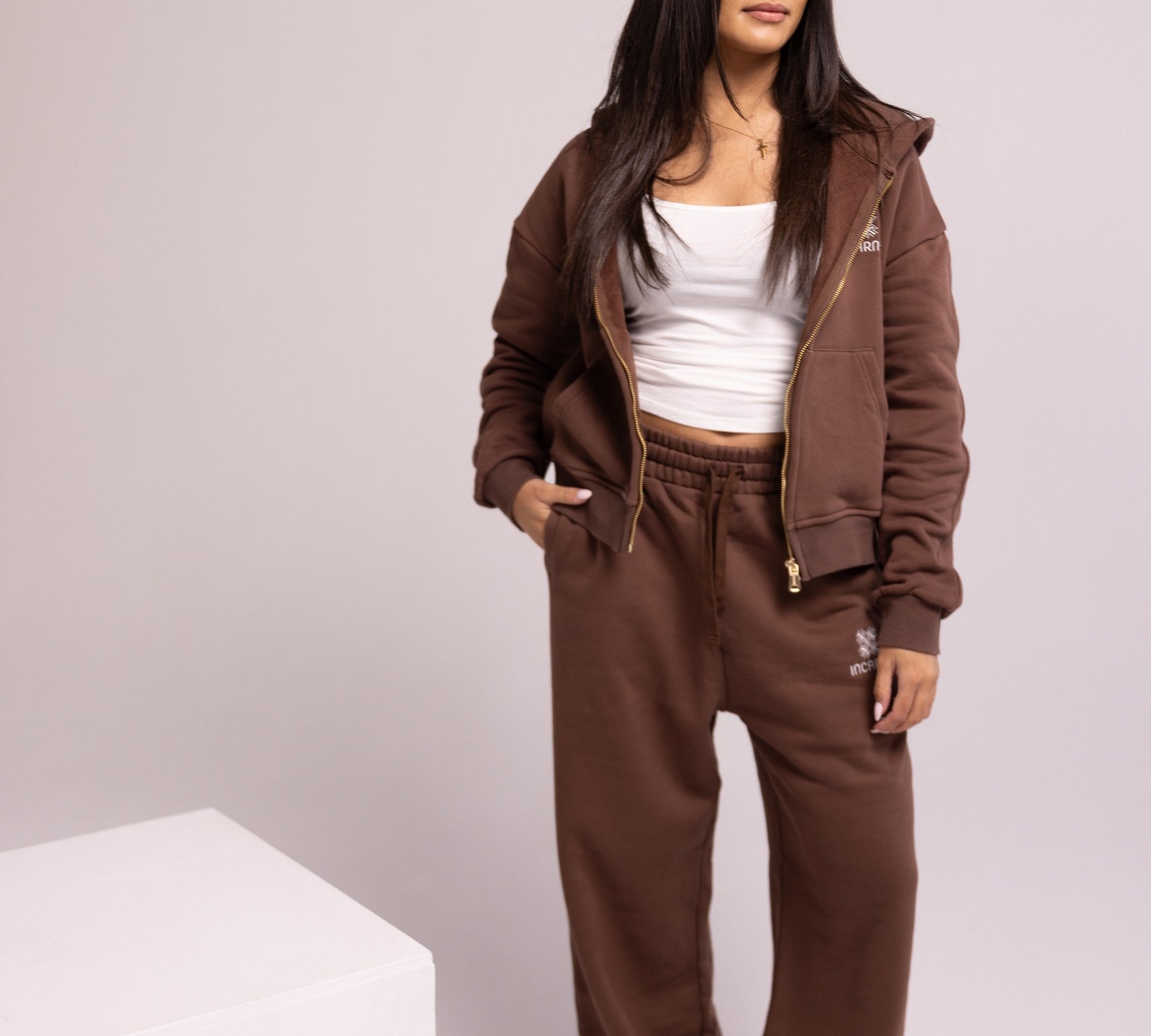 Person wearing a brown tracksuit with a white top on a plain background