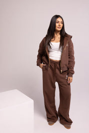 Person wearing a brown tracksuit with a white top on a plain background
