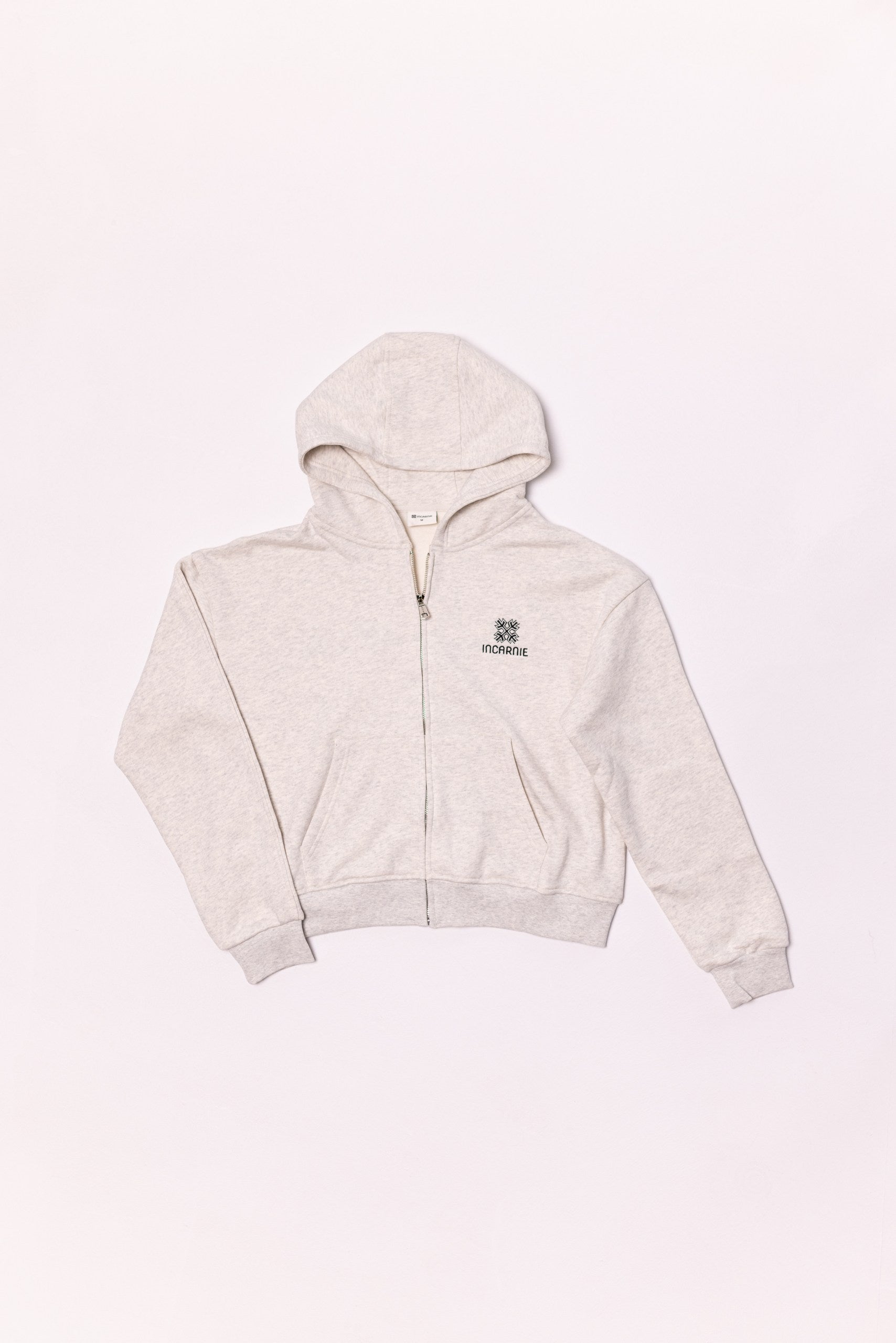 Beige hoodie with a brand logo on a light pink background