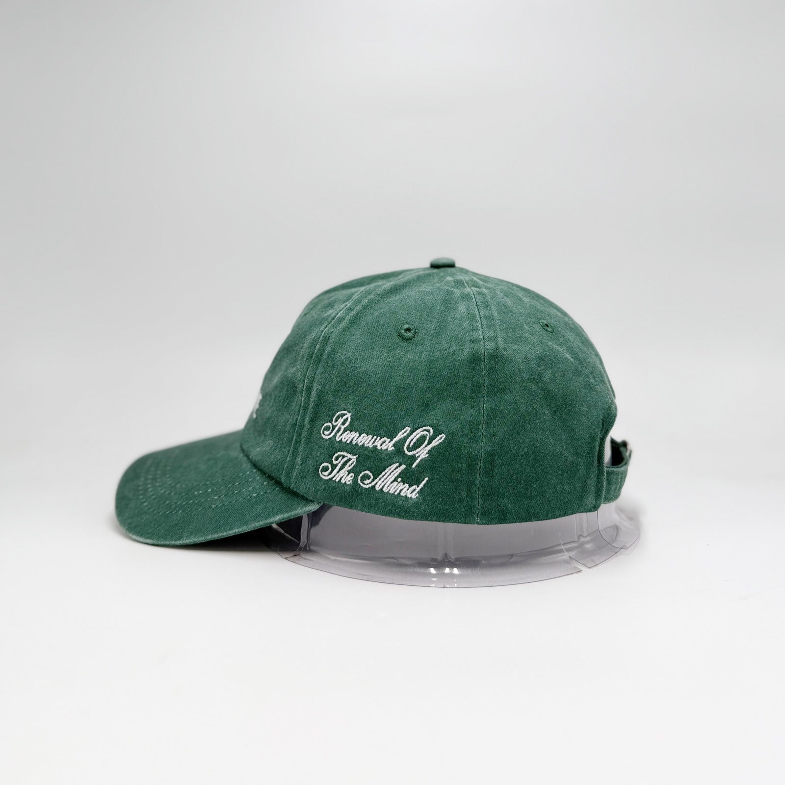 Green cap with white text on a clear stand against a light gray background