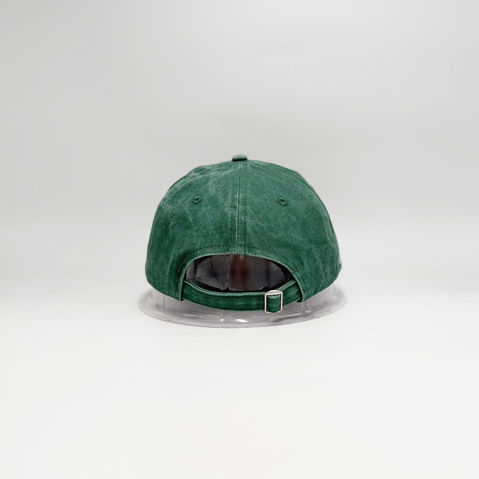 Green baseball cap on a clear stand against a white background